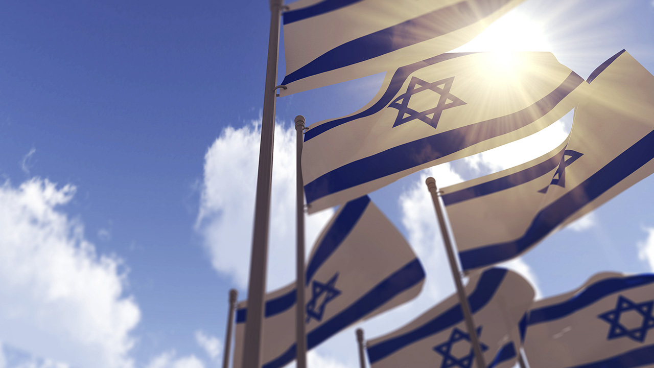 Israel flags against a blue sky with sun shining through