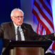 Picture of Sen. Bernie Sanders speaking with American flag in the background