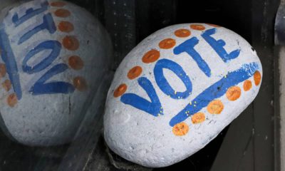 Photo of a stone painted with the word "VOTE" painted on it