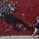 Photo of a woman walking past a mural in downtown Tehran