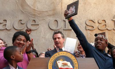 Photo of Gov. Gavin Newsom surrounded by Assemblywoman Shirley Weber and members of the Clark family after the signing of AB 392 lFam