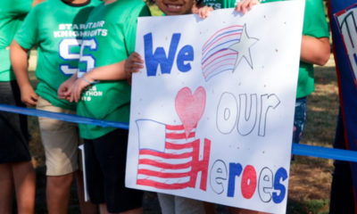 Photo of students holding a homemade sign saluting their heroes