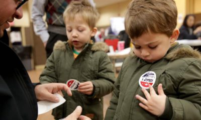 Photo of kids putting on an "I Voted" sticker