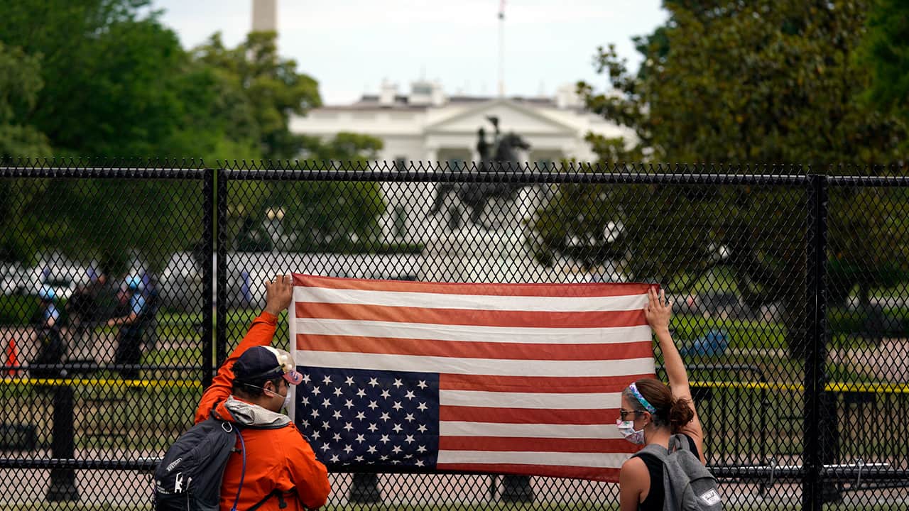 Photo of people holding a flag upside down at the white house