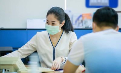 Image of a woman in a bank wearing a COVID-19 mask across from a customer